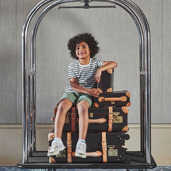 Boy sitting on suitcases on The Berkeley's luggage trolley