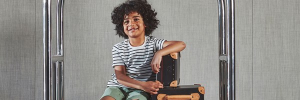 boy sitting on suitcases on The Berkeley's luggage trolley