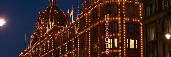 Harrods’ exterior at night, outlined in warm festive lights against a dark sky.