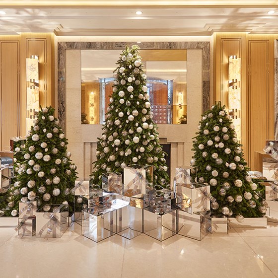 Three christmas trees decorated in gold and silver in hotel lobby