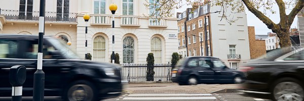 View of crossing and white residential  buildings in London, with black taxis