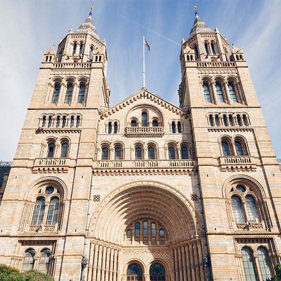 View of the front of the National History Museum, an impressive building with blue sky  in the background.