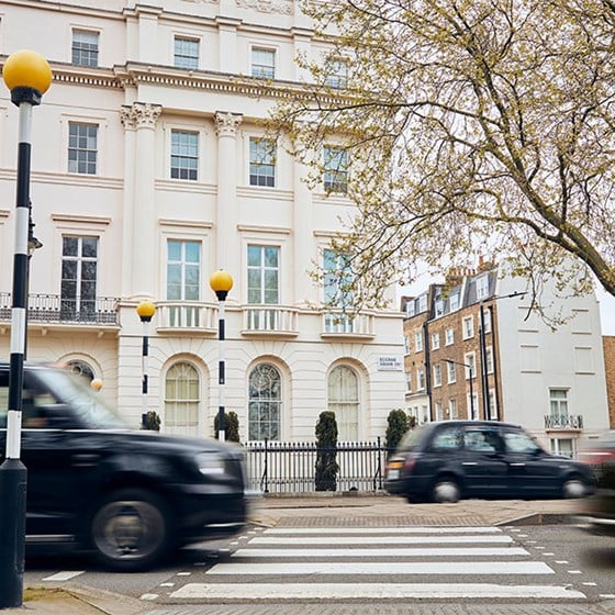 View of crossing and white residential buildings in London, with black taxis