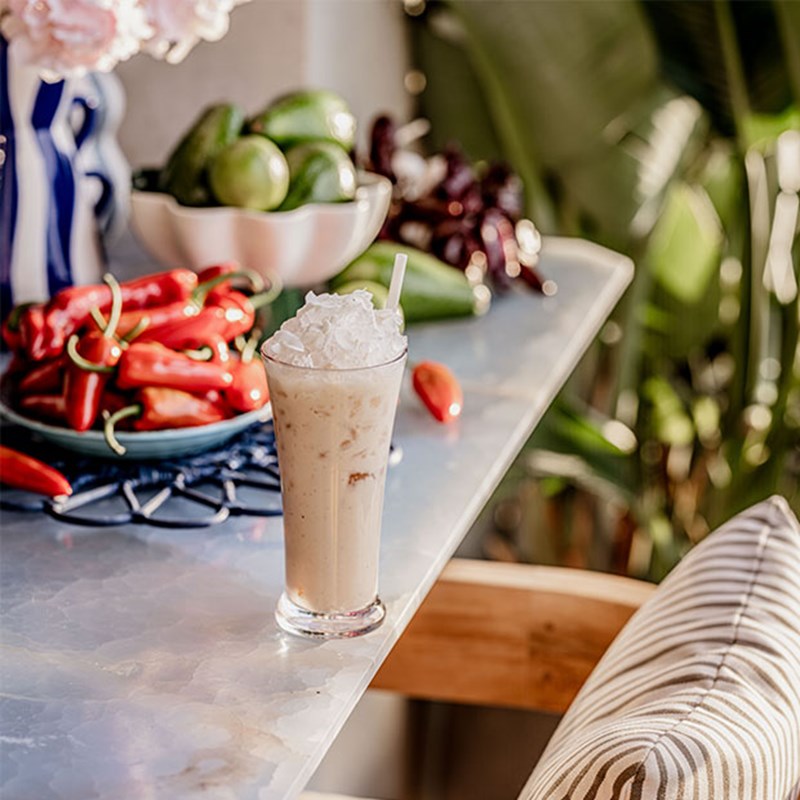 Iced coffee served on the bar at The Berkeley Rooftop Bar, with a bowl of chillies and limes in the background.