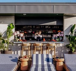 The Berkeley Rooftop Bar on a sunny day. with a barman stood behind shaking a cocktail.