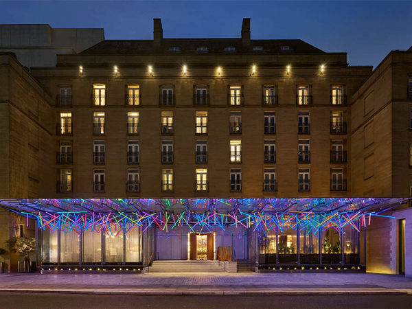 The Berkeley hotel façade at night with a colourful illuminated canopy and lit windows along the street.