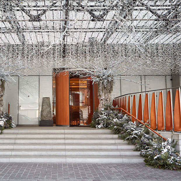 The grand entrance of The Berkeley, elegantly dressed with snowy garlands, frosted branches, and sparkling holiday lights, offering a sophisticated and festive welcome.