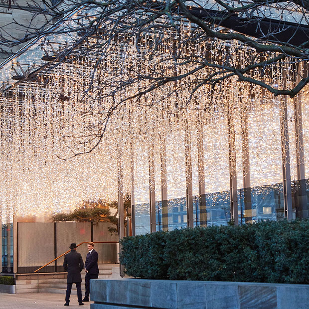 An intricately decorated gingerbread house with green and white icing, candy cane accents, and delicate piping details, evoking a whimsical holiday charm.