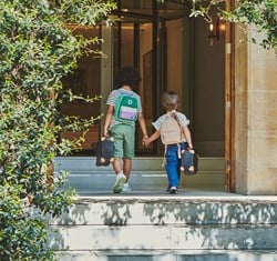 Back view of boy and girl holding hands wearing mini rucksacks