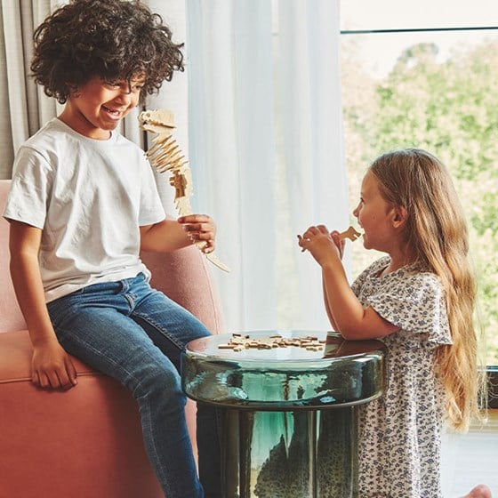 Boy and girl laughing playing with build-your-own wooden dinosaur