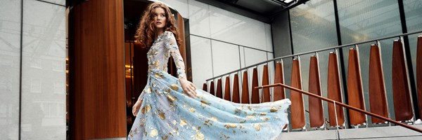 woman with red hair in blue and gold long dress flowing behind her on the steps to The Berkeley