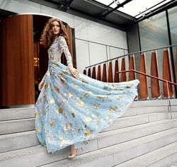 woman with red hair in blue and gold long dress flowing behind her on the steps to The Berkeley