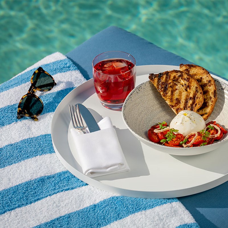 A plate of toasted bruschetta and sunglasses on the edge of the pool