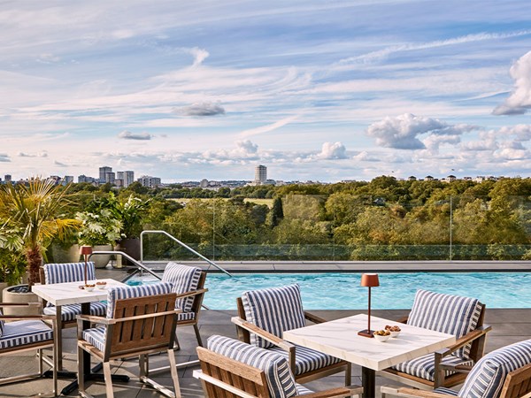 tables and chairs by the Berkeley rooftop pool, with a view over Hydepark and tall city buildings