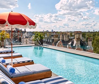 Rooftop pool at The Berkeley with blue and white striped beds and a red umbrella with views of Hyde Park