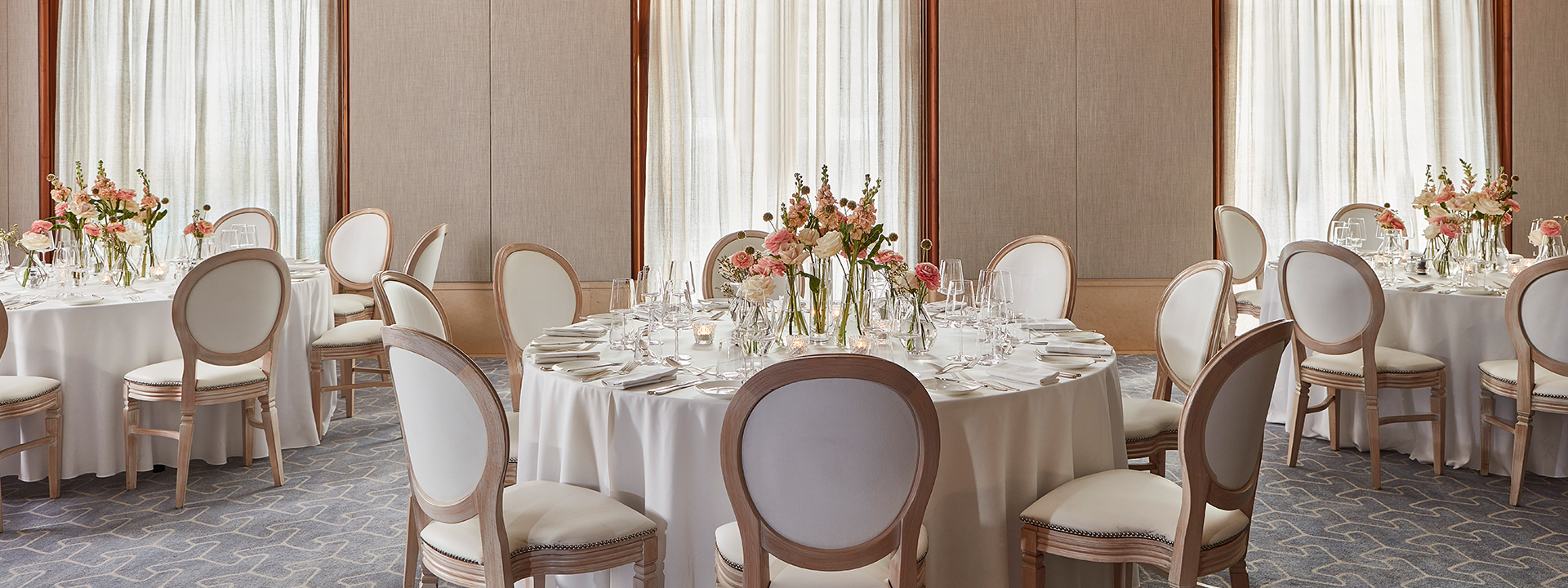 Belgravia room set up for a private event with table, chairs and flower arrangement.