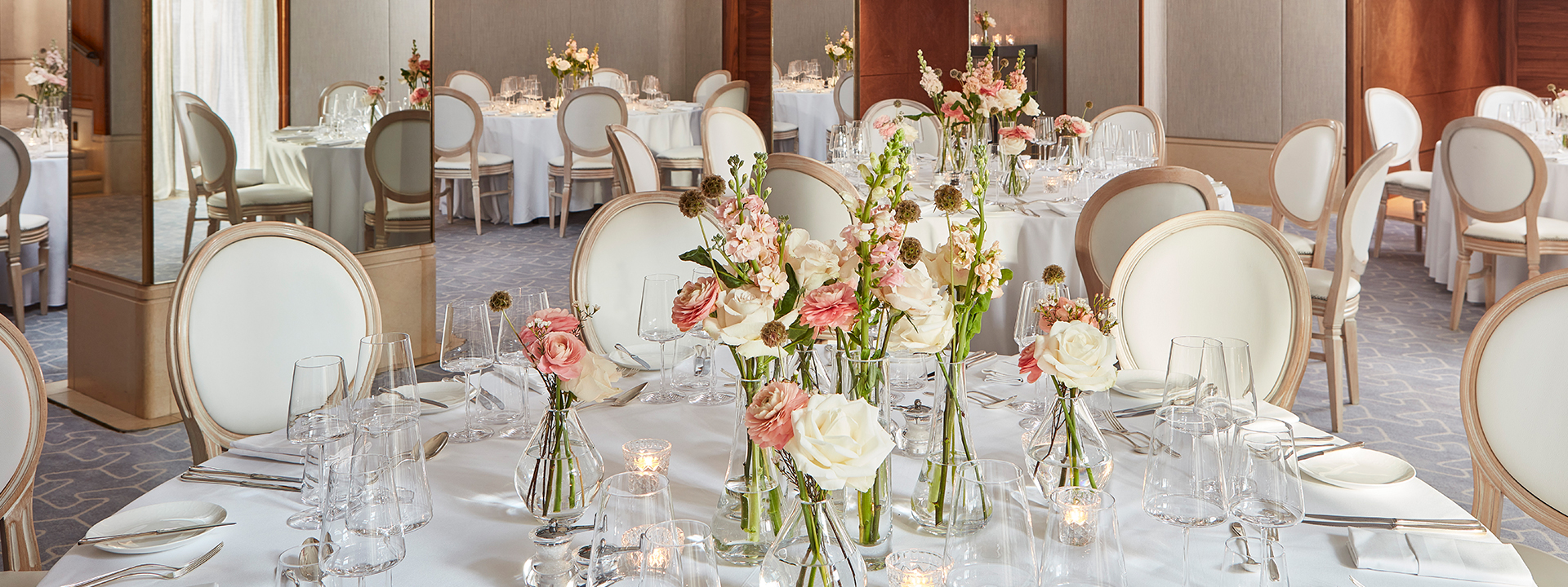 Belgravia room set up with tables, chairs, and flower arrangement