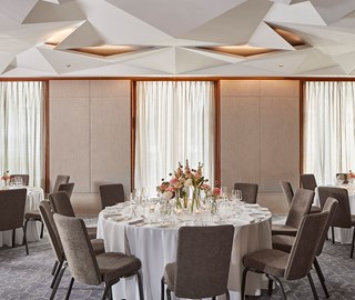 Belgravia room set up for a business event with table, chairs and flower arrangement.