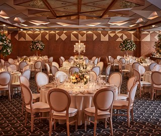 Ballroom set up for a private event with tables, chairs and flower arrangement.