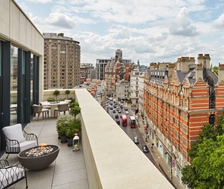 Terrace of the Hyde Park Penthouse at The Berkeley with armchairs and a firepit, and a view on Belgravia