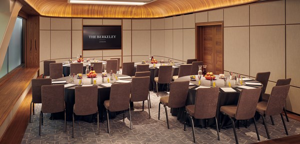 Three tables set up in a meeting room in a corporate layout with work related items on the tables