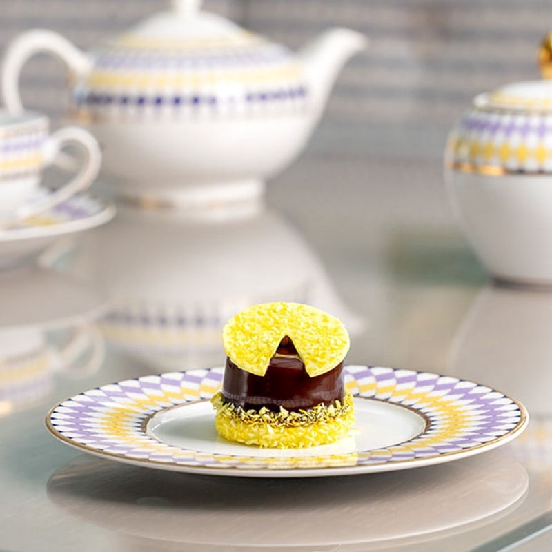 Chocolate small cake with yellow decoration on a plate