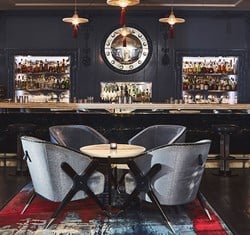 Four deep blue lounge chairs around a table in front of the bar with blue interior