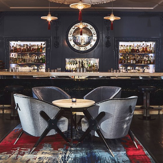 Four deep blue lounge chairs around a table in front of the bar with blue interior