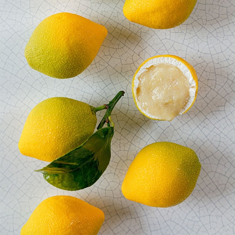 Bright yellow lemons, with one halved to show a smooth pale citrus mousse filling.