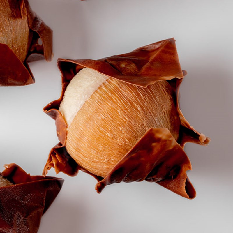 A spherical chestnut-inspired dessert wrapped in thin, crinkled brown pastry.