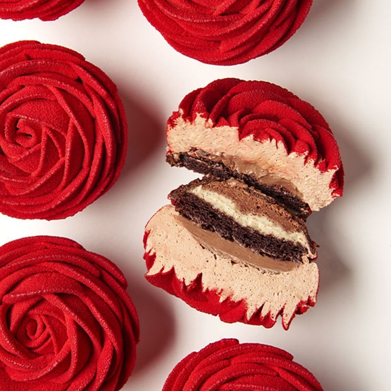 Red rose-shaped cakes, with one cut open to show layers of chocolate sponge, cream, and mousse.