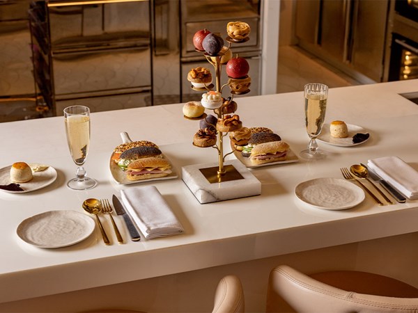 Elegant countertop afternoon tea setting with filled baguettes, scones, and a tiered display of patisserie at Cédric Grolet.