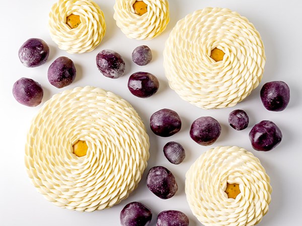 White rosette-shaped pastries paired with glossy purple fruit-shaped confections.