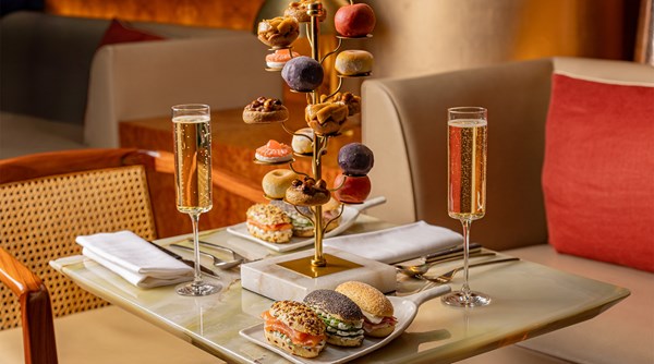 Afternoon tea setup with sparkling wine, savoury bites, and a tree-like stand of signature pastries.