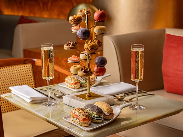 Elegant afternoon tea display with mini pastries, savoury sandwiches, and two glasses of champagne.