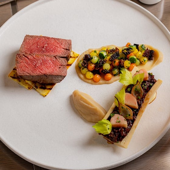 A dish with beef, bone marrow and a side of vegetables beautifully laid out at the Collins Room at The Berkeley.