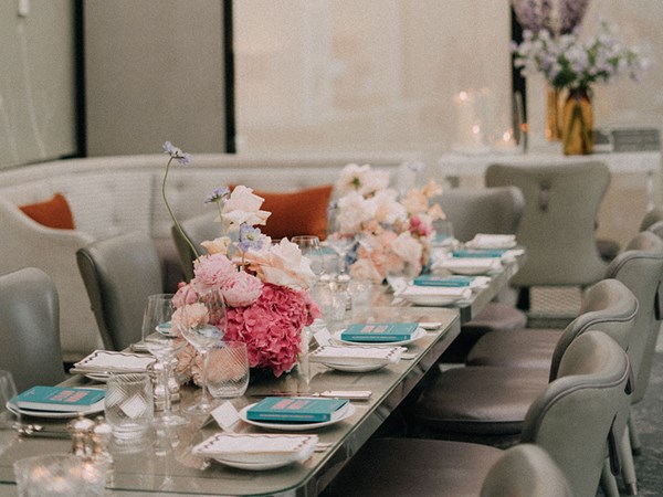 Table laid with blue napkins and pink flowers with candles in the Collins Room