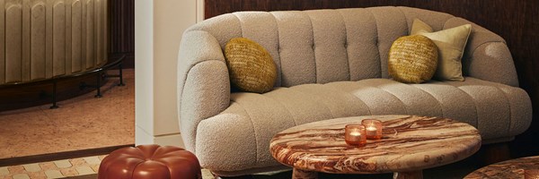 A cosy lounge corner at The Berkeley Bar, featuring a plush tufted sofa with textured cushions, sculptural marble tables, and soft ambient lighting.