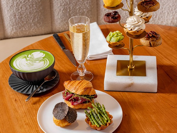 Goutea featuring tiered patisserie, savoury selection on plates and a glass of champagne