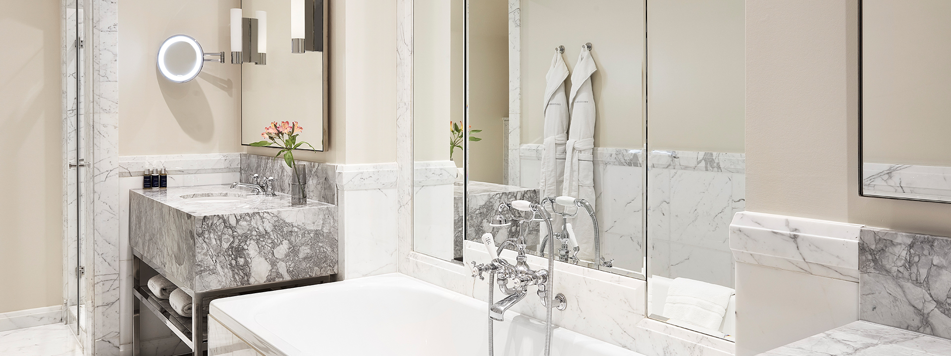 Large ensuite marble bathroom in the Belgravia Room, decorated with floral arrangements.