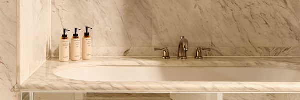 Park Suite bathroom featuring wooden cabinetry, two stone sinks, black fixtures, and a white freestanding bathtub.