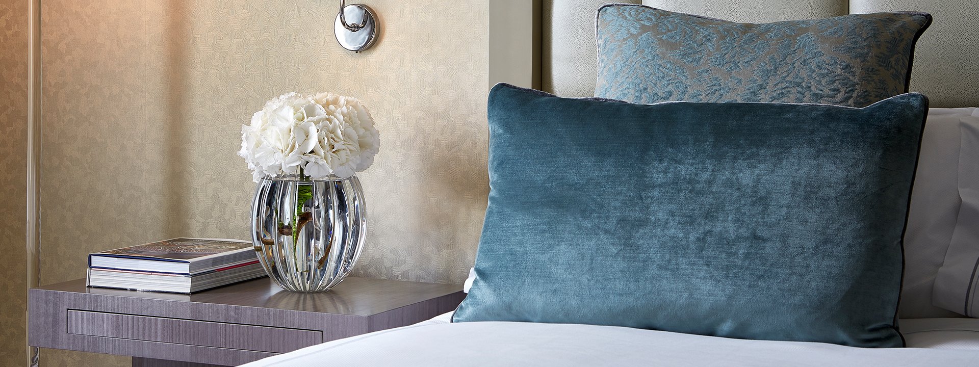 Rich fabrics and luxurious designs of blue cushions in the Chelsea suite, with a white flower arrangement.