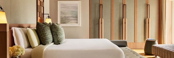 Elegant penthouse bedroom featuring a large bed with textured pillows, ambient lighting, and natural wood paneling for a calm and refined atmosphere.