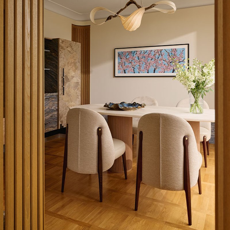 Elegant dining room featuring a cream oval table surrounded by upholstered chairs, a dramatic sculptural chandelier, and framed cherry blossom artwork enhancing the serene atmosphere.