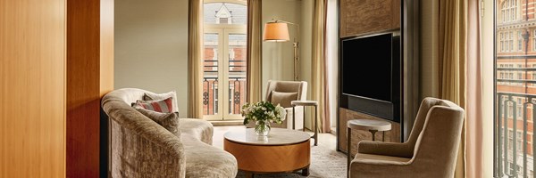 An intimate lounge setting with curved velvet seating, modern lounge chairs, and a marble coffee table, with sweeping views over Knightsbridge’s architectural skyline.