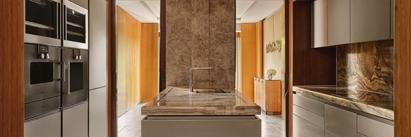 A sleek designer kitchen blending natural stone, warm wood cabinetry, and high-spec appliances, with a central island ideal for private dining or culinary experiences.