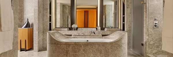 A sculptural marble bathroom with a freestanding bath, dual vanity sinks, and warm integrated lighting, exuding calm and contemporary luxury.