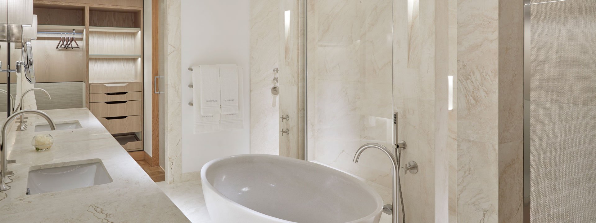 A view of the beige and modern ensuite bathroom with a freestanding bathtub and walk-in shower in the Knightsbridge Suite.