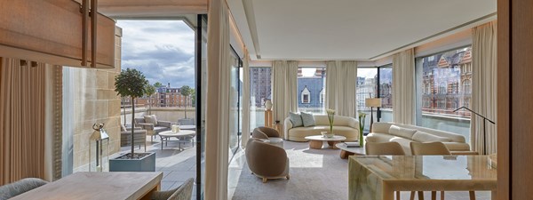 Light filled living area of penthouse suite with cream furniture and marble bar