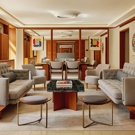 A symmetrical view of a refined living area with soft grey seating, warm wooden cabinetry, and modern abstract artworks creating a sense of harmony.